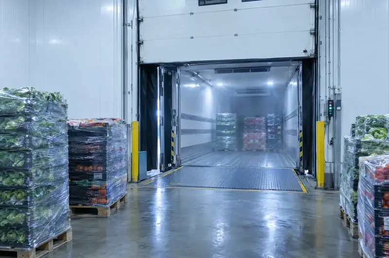 Insulated cold store dock door open onto a refrigerated trailer with a dock leveller in place