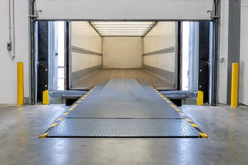 Telescopic-lip dock leveller extended into an empty box trailer